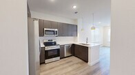 This well-designed one-bedroom, one-bathroom unit offers a thoughtful layout across a single floor, making efficient use of its compact footprint. The open-concept kitchen and living area serves as the heart of the space, featuring dark wood cabinetry that extends to the ceiling for ample storage, crisp white quartz countertops, and a full suite of stainless steel appliances including a range, over-the-range microwave, dishwasher, and French door refrigerator. A peninsula with an undermount sink and stylish globe pendant lights adds both function and visual interest, while light wood-look plank flooring runs seamlessly throughout the entire unit. The bedroom is a bright, comfortable retreat with a large window fitted with blinds, a ceiling fan with recessed lighting, and direct access to a walk-in closet outfitted with built-in shelving and dual hanging rods. A second closet provides additional storage. The bathroom features a dark wood floating vanity with a white countertop and undermount sink, maintaining the modern aesthetic found throughout. A dedicated laundry area adds everyday convenience. Clean white walls, recessed lighting, and natural light from multiple windows contribute to an airy, contemporary ambiance throughout the space.