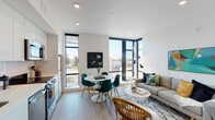 Located on Shattuck Avenue in Berkeley, California, this single-floor unit showcases a contemporary design aesthetic characterized by clean lines, bright white walls, and light hardwood flooring throughout. The open-concept living and dining area serves as the heart of the space, anchored by striking floor-to-ceiling corner windows framed in matte black that flood the room with natural light and offer open views of the surrounding Berkeley neighborhood. The living area provides a comfortable, well-proportioned space for relaxing and entertaining.

The kitchen is efficiently designed with crisp white cabinetry, light countertops, a textured tile backsplash, open display shelving, and a full suite of stainless steel appliances including a dishwasher, range, and microwave. The bedroom is a calm, private retreat featuring recessed lighting, a louvered closet, and a distinctive sliding frosted-glass panel partition that adds a modern, architectural touch while offering flexible separation from the hallway. A full bathroom features a floating white vanity, tile flooring, and a shower with curtain. The consistent use of neutral tones and contemporary finishes creates a cohesive, modern ambiance throughout the entire space.