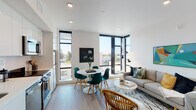 Located on Shattuck Avenue in Berkeley, California, this single-floor unit showcases a contemporary design aesthetic characterized by clean lines, bright white walls, and light hardwood flooring throughout. The open-concept living and dining area serves as the heart of the space, anchored by striking floor-to-ceiling corner windows framed in matte black that flood the room with natural light and offer open views of the surrounding Berkeley neighborhood. The living area provides a comfortable, well-proportioned space for relaxing and entertaining.

The kitchen is efficiently designed with crisp white cabinetry, light countertops, a textured tile backsplash, open display shelving, and a full suite of stainless steel appliances including a dishwasher, range, and microwave. The bedroom is a calm, private retreat featuring recessed lighting, a louvered closet, and a distinctive sliding frosted-glass panel partition that adds a modern, architectural touch while offering flexible separation from the hallway. A full bathroom features a floating white vanity, tile flooring, and a shower with curtain. The consistent use of neutral tones and contemporary finishes creates a cohesive, modern ambiance throughout the entire space.