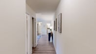This thoughtfully designed 2-bedroom, 2-bathroom single-floor residence offers a practical and comfortable layout across a well-utilized footprint. Wood-look flooring flows consistently throughout, lending a cohesive and modern aesthetic to every room.

A welcoming hallway serves as the spine of the home, connecting all living spaces with clean white walls accented by framed artwork. The living room is a comfortable gathering space featuring a large sliding glass door with vertical blinds that invites natural light. The adjacent dining area includes a chandelier overhead and a window with natural light, creating an inviting space for meals.

The kitchen is equipped with warm maple cabinetry, a full suite of white appliances including a refrigerator, electric range, built-in microwave, and dishwasher, along with a double basin sink and ample counter space.

The primary bedroom is generously sized, featuring multiple windows that bring in natural light, and is complemented by a private bathroom with a tub-shower combination. The second bedroom includes a walk-in closet and its own window for natural light. A second full bathroom serves the remaining rooms. A dedicated laundry area houses a stacked washer and dryer unit, adding everyday convenience to this well-rounded home.