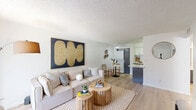 Located at 3330 West Greenway Road in Phoenix, AZ, this one-bedroom, two-bathroom residence offers a thoughtfully designed single-floor layout that maximizes every square foot. The open-concept living room welcomes residents with light wood-style flooring, a textured ceiling, and a large sliding glass door that fills the space with natural light. The living area flows seamlessly into a dedicated dining nook, complete with a ceiling fan, before connecting to the kitchen. The galley-style kitchen is well-appointed with gray cabinetry, white subway tile backsplash, light countertops, black appliances including a refrigerator, electric range, and dishwasher, and a stainless steel sink. A stacked in-unit washer and dryer is conveniently tucked adjacent to the dining area. The bedroom features plush carpeting, a window with natural light, and direct access to a spacious walk-in closet with built-in shelving and hanging rods on multiple walls. Two bathrooms serve the unit, including one with an extended vanity countertop and a wide mirror. Clean white walls and consistent finishes throughout give the home a bright, cohesive ambiance well-suited for comfortable everyday living in the Phoenix area.