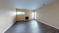This single-floor residence offers a thoughtfully designed layout with a neutral color palette of warm beige and white tones throughout. The living area serves as a central gathering space, anchored by a built-in fireplace framed in a matching surround. Multiple windows allow natural light to filter in, enhancing the open, airy feel of the room.

The kitchen is outfitted with light wood cabinetry, dark countertops, and a full suite of stainless steel appliances, including a refrigerator and dishwasher. Light wood-style flooring runs through the kitchen and transitions to darker wood-look flooring in the hallway and living areas.

A central hallway connects the main living spaces to the private areas of the home, with a thermostat conveniently mounted along the corridor. The bedrooms feature plush carpeting and ceiling fans, providing comfortable, adaptable spaces. One bedroom includes a spacious walk-in closet with built-in shelving and hanging rods.

Two bathrooms serve the residence: one features a tub-shower combination with light tile flooring and a wood-toned vanity, while the second offers a glass-door shower enclosure. An in-unit laundry area with a full-size washer and dryer, topped by upper cabinetry for storage, adds everyday convenience.