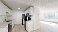 This single-floor unit at 5729 N Garrett St in Garden City, Idaho offers a straightforward and functional layout. The galley-style kitchen is well-equipped, featuring light wood cabinetry lining both walls, laminate countertops, a double sink, a white electric range, and a refrigerator. A window at the end of the kitchen allows natural light to filter into the space. The kitchen opens directly into a spacious living area finished with light-toned laminate wood flooring, a large window that brings in additional natural light, and a baseboard heating unit along the wall.

The bedrooms are carpeted and offer neutral wall tones throughout. One bedroom includes a wall-mounted air conditioning unit, a ceiling fan, a window, and baseboard heating. Additional bedrooms provide similarly neutral, move-in ready spaces with carpet flooring and textured ceilings consistent with the rest of the unit. The bathroom includes a full-size soaking tub and shower combination with clean white surround walls. Throughout the unit, textured ceilings are a consistent architectural detail. Baseboard heating is present in multiple rooms, providing a functional heating solution across the entire single-floor layout.