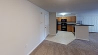 This single-floor residential unit offers a well-organized, functional layout designed for comfortable everyday living. The open-concept living and dining area is finished with plush wall-to-wall carpeting and neutral-toned walls, creating a warm and inviting atmosphere. A breakfast bar peninsula connects the living space to the kitchen, enhancing the sense of openness and providing additional seating and counter space.

The kitchen is fully equipped with a complete suite of black appliances, including a refrigerator, electric range, built-in microwave, and dishwasher. Warm oak cabinetry lines the walls, offering generous storage, while dark countertops provide a practical and contrasting finish. Light tile flooring runs throughout the kitchen for easy maintenance.

The bedrooms are carpeted and feature neutral walls, with windows fitted with horizontal blinds that allow for natural light and privacy. Ceiling fans are present, contributing to year-round comfort. Each bedroom offers convenient access to closet storage.

The bathroom is clean and functional, featuring a wide vanity with an oak cabinet base, a large wall mirror with overhead lighting, and a full-size soaking tub with a shower combo. Light tile flooring completes the space with a bright, airy feel. Throughout the unit, white panel doors and clean baseboards contribute to a cohesive, well-maintained interior.