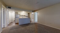 Located at 736 E 12th Ave in Emporia, Kansas, this single-story home offers four bedrooms and one bathroom across a well-organized floor plan. The combined kitchen and living area forms the central hub of the home, where an open-concept peninsula separates the kitchen from the carpeted living space. The kitchen is equipped with white cabinetry, a double-basin sink, an electric range with a range hood, and a full-size refrigerator, complemented by dark hardwood-style flooring. The living room benefits from natural light streaming through large windows fitted with horizontal blinds, and provides direct access to the front entry door. Each of the four bedrooms features wall-to-wall carpeting and neutral-toned walls, with several rooms offering windows that bring in natural light. One bedroom features exposed painted cinder block walls, adding a distinctive architectural detail, while the primary bedroom includes a double closet with built-in hanging rods, providing generous storage. The bathroom includes a window for natural ventilation and is finished with hardwood-style flooring. Textured ceilings are present throughout the home, and the overall neutral color palette creates a clean, functional living environment throughout.