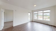 Located at 4255 Maple Street SE in Olympia, Washington, this single-floor residence offers a clean, contemporary design throughout. The open-concept living area is anchored by wood-style plank flooring and crisp white walls, with large windows and a glass-panel door that flood the space with natural light and provide elevated views of the surrounding neighborhood.

The kitchen is thoughtfully designed with dark cabinetry, light quartz countertops, and a full suite of stainless steel appliances, including a range, microwave, refrigerator, and dishwasher. A peninsula with a deep stainless sink connects the kitchen to the living area, creating an efficient and social layout. A dedicated in-unit laundry closet with a stacked washer and dryer adds everyday convenience.

The bedrooms feature plush carpeting, generous windows with neighborhood views, and baseboard heating. The bathroom is finished with a dark vanity, light quartz countertop, and chrome fixtures, maintaining the consistent modern aesthetic found throughout the unit.

Overall, the space presents a well-coordinated palette of dark cabinetry, neutral tones, and wood-style flooring, resulting in a contemporary and functional living environment.