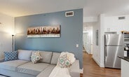 Located in Princeton, FL, this thoughtfully designed 2-bedroom, 2-bathroom residence offers a functional single-floor layout with modern finishes throughout. The living room serves as a welcoming centerpiece, featuring warm wood-look flooring, a distinctive blue accent wall, and sliding glass doors that open to a private patio with outdoor views, allowing natural light to fill the space.

The kitchen is a standout feature, boasting crisp white shaker cabinetry, dark granite countertops, stainless steel appliances, a center island with a built-in dishwasher, and pendant lighting overhead. An adjacent dining area provides a seamless space for everyday meals or entertaining.

Both bedrooms are comfortably proportioned with wood-look flooring, natural light from window blinds, and neutral accent walls. The primary bedroom offers a calm, restful atmosphere with ample closet space. The two bathrooms are well-finished, each featuring a tub-shower combo with tile surround, dark-toned vanities with granite countertops, and bright vanity lighting.

Additional highlights include three closets, two hallways, a dedicated laundry area, and a utility room, ensuring practical storage and convenience. The overall ambiance is clean, contemporary, and move-in ready.