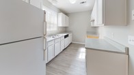 Located at 3637 Pleasantdale Rd in Atlanta, Georgia, this single-floor unit offers a clean, neutral aesthetic with functional design throughout. The living area features durable wood-look flooring, soft gray walls, and a ceiling fan, creating a comfortable and versatile space. French doors open to an outdoor area, allowing natural light to fill the room and providing a pleasant connection to the exterior.

The kitchen is well-appointed with white cabinetry, light countertops, a double-basin sink, a dishwasher, and a full-size refrigerator. A window above the sink brings in additional natural light, enhancing the bright, practical workspace. Light-toned vinyl flooring completes the kitchen's clean look.

The bedroom features plush carpeting, a large window with views of surrounding greenery, and a textured ceiling, offering a quiet and comfortable retreat. The hallway connects the bedroom to the kitchen area and includes access to a bathroom with a vanity featuring white cabinetry, a countertop sink, and a mirrored medicine cabinet.

The bathroom includes a full tub and shower combination with white tile surround, chrome fixtures, and wood-look tile flooring. Throughout the unit, crisp white trim, textured ceilings, and consistent neutral tones create a cohesive and move-in-ready environment.