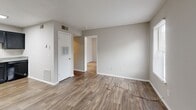 Located at 2050 Old Clinton Rd in Macon, Georgia, this single-floor unit offers a practical and efficient layout within a compact footprint. The open-plan kitchen and living area form the heart of the space, unified by warm wood-look vinyl flooring and a neutral gray color palette that lends a clean, modern feel throughout.

The kitchen is well-equipped with dark espresso-toned cabinetry spanning both upper and lower storage, a double-basin sink with light countertops, a black electric range, and a dishwasher. Overhead fluorescent lighting provides strong task illumination, while HVAC vents ensure comfortable year-round climate control.

The living area offers an open, flexible space with smooth walls, a textured ceiling, and direct access to an additional room via an interior doorway. A white paneled door provides entry access, and wall-mounted utility panels are neatly integrated along one wall.

The adjoining room features two windows fitted with horizontal blinds that allow natural light to filter in while maintaining privacy, along with the same wood-look flooring for a cohesive aesthetic. The space is completed with clean white baseboards throughout and a straightforward, functional design suited to comfortable everyday living.