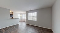 This single-floor residence offers a clean, contemporary design with a neutral color palette and thoughtful layout throughout. The open-concept living and dining area is anchored by rich, dark hardwood-style flooring that extends seamlessly across the main living spaces. Large windows dressed with horizontal blinds fill the area with natural light, while a decorative chandelier above the dining space adds a refined touch. A breakfast bar connects the dining area to the kitchen, which features dark espresso cabinetry, granite-style countertops, and black appliances including a refrigerator, electric range, and built-in microwave. The kitchen's hardwood-style flooring continues the cohesive aesthetic of the main living area. The bedrooms offer plush carpeting, neutral walls, and windows that provide ample natural light. Each room offers generous proportions suitable for a variety of furnishing arrangements. The bathrooms are well-finished: one features a glass-enclosed shower stall with tile surround and dark wood vanity cabinetry, while the second includes a full tub-shower combination with tile surround, tile flooring, and a white vanity countertop. Overall, the space presents a move-in-ready environment with consistent, practical finishes throughout.