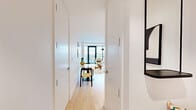 Located at 44 Hudson St in Yonkers, NY, this modern residence offers a well-planned single-floor layout that maximizes every square foot. Light hardwood flooring flows throughout, complemented by crisp white walls that create a clean, contemporary aesthetic.

The open-plan kitchen and dining area serves as the heart of the home, featuring a wood-paneled island with a white quartz countertop and integrated sink, stainless steel appliances including a range, microwave, and refrigerator, and a combination of wood-toned and matte upper cabinetry. Marble-look tile flooring anchors the kitchen zone, while a dining area with a round marble-top table sits just alongside.

The living room is bright and airy, with floor-to-ceiling windows and access to an outdoor balcony offering views of the surrounding Yonkers cityscape. A wall-mounted mini-split system provides climate control.

The bedroom is equally light-filled, featuring its own floor-to-ceiling windows with balcony access and city views, a closet, and a wall-mounted mini-split unit. The bathroom is finished with large-format gray stone tile, a floating wood vanity with an illuminated mirror cabinet, and a soaking tub. Three closets and an in-unit laundry room round out the functional amenities of this well-appointed residence.