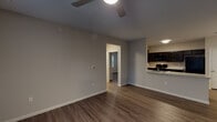 This well-appointed 3-bedroom, 2-bathroom single-story residence offers a thoughtfully designed open floor plan that maximizes both space and functionality. Wood-look plank flooring flows throughout the main living areas and bedrooms, providing a warm, cohesive aesthetic complemented by neutral gray walls and clean white trim.

The kitchen is a standout feature, showcasing dark espresso cabinetry with sleek hardware, light granite-style countertops, a kitchen island with a built-in sink, and black appliances including a range and microwave. The kitchen opens seamlessly into the main living area, which is bright and spacious with a ceiling fan overhead.

Each of the three bedrooms is generously sized, featuring ceiling fans, wood-look flooring, and ample closet space with built-in shelving. Natural light filters in through large windows dressed with horizontal blinds, offering views of the surrounding greenery.

Both bathrooms are finished consistently with dark vanity cabinetry, white countertops, large mirrors, and full tub/shower combinations set over clean white tile flooring. A dedicated in-unit laundry closet houses a full-size washer and dryer, adding everyday convenience. Additional storage is available throughout, rounding out this practical and comfortable home.