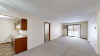 This single-floor unit offers a practical and efficient layout across two bedrooms and three bathrooms. The open living room is finished with neutral carpet and features a sliding glass door that brings in natural light and provides outdoor views, complemented by a wall-mounted air conditioning unit. Textured ceilings and warm beige walls maintain a consistent, understated aesthetic throughout the space.

The galley-style kitchen is equipped with warm-toned wood cabinetry, ample upper and lower storage, light-colored countertops, and white appliances including a range, microwave, and refrigerator. Tile flooring and a ceiling light fixture complete the functional space.

Both bedrooms are carpeted and feature wood-framed windows with exterior views and baseboard heating. Each room offers a comfortable, quiet setting. Closets include wire shelving systems for organized storage.

The three bathrooms are cleanly finished with tub-shower combinations and neutral tones. A hallway connects the private areas of the unit to the main living spaces, contributing to a straightforward and navigable floor plan throughout.