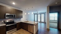 This single-story, one-bedroom, one-bathroom unit offers a thoughtfully designed open-concept layout that maximizes its comfortable footprint. The kitchen serves as a central highlight, featuring dark espresso cabinetry, granite countertops, a tile backsplash, and a full suite of stainless steel appliances including a refrigerator, electric range, microwave, and dishwasher. A peninsula island with an undermount sink provides additional prep space and casual seating, while pendant lighting above adds a modern, polished touch. Wood-style flooring extends throughout the main living areas, creating a warm and cohesive aesthetic.

The living area is bright and open, benefiting from large double doors with shuttered windows that invite natural light and connect the interior to the outdoors. A ceiling fan overhead enhances comfort year-round. The bedroom is a calm, well-sized retreat finished with plush carpet, a ceiling fan, and a window that brings in additional natural light.

The bathroom is clean and functional, featuring the same granite countertop and dark cabinetry found in the kitchen, a full tub-shower combination, wood-style flooring, and a large mirror that adds depth to the space. Overall, the unit presents a modern, cohesive design throughout.