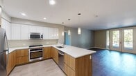 This contemporary apartment, located in Revel Campbell, offers a harmonious blend of style and functionality across its 1470 square feet. The heart of the home is an open-concept kitchen and living area, showcasing a sleek design with white upper cabinets contrasting warm wood lower cabinets. Stainless steel appliances and a generous island with pendant lighting enhance the kitchen's appeal.

The living spaces boast large windows and glass doors, flooding the rooms with natural light and providing views of the surrounding greenery. Dark hardwood floors in the living areas create a sophisticated ambiance, while plush carpeting in the bedrooms ensures comfort.

The primary bedroom, spanning 230 square feet, offers ample space for relaxation. Two additional bedrooms provide versatility for various needs. The bathrooms feature modern fixtures, including a glass-enclosed shower in one and a spacious vanity in another.

Storage solutions are thoughtfully integrated, with built-in closet systems maximizing space efficiency. The apartment's neutral color palette creates a canvas for personalization, while recessed lighting throughout adds to the modern aesthetic.

Situated in Campbell, CA, this apartment combines urban convenience with a touch of nature, as evidenced by the tree-lined streets visible from the balcony. This residence offers a perfect balance of comfort, style, and location for contemporary living.