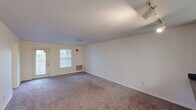This single-floor residence offers four bedrooms and four bathrooms, providing ample space for comfortable living. The combined kitchen and living room serves as the heart of the home, with the living area featuring plush wall-to-wall carpeting, a door leading to a private balcony, and a window that draws in natural light and offers open views of the surrounding neighborhood and green landscape beyond. The kitchen is well-equipped with white cabinetry, dark countertops, a double sink, and white appliances including a stove, over-the-range microwave, and refrigerator, all set over tile flooring. Each of the four carpeted bedrooms is a comfortable size, with several rooms featuring ceiling fans with integrated lighting. The bedrooms are serviced by dedicated closets, offering practical storage throughout. The bathrooms include at least one featuring a double-sink vanity with dark countertops and white cabinetry, alongside tiled shower and tub enclosures. Two hallways connect the layout efficiently, and a welcoming entrance completes the floor plan. The space is distributed thoughtfully across its single level, making it highly accessible and functional for everyday living.