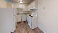 Located at 2505 Verde Dr in Colorado Springs, CO, this single-floor residence offers a practical and well-organized layout suited for comfortable everyday living. The kitchen is equipped with white cabinetry, ample counter space, and a full suite of white appliances including a refrigerator, dishwasher, and electric range with overhead ventilation. Wood-style flooring runs throughout the kitchen and connecting areas, creating a clean and cohesive look. The living area transitions seamlessly from the kitchen, featuring neutral carpet, a baseboard heating unit, and an open feel that allows for flexible furniture arrangement. Natural light enters through a window dressed with vertical blinds, contributing to a bright and airy atmosphere. The bedroom is carpeted and generously sized, with a built-in closet offering dedicated storage space. A window with vertical blinds allows natural light into the room, while a baseboard heater ensures year-round comfort. The bathroom features wood-style tile flooring, a full-size soaking tub with a tiled surround, and clean white fixtures throughout. The overall design of the space is straightforward and neutral, with light-toned walls and consistent finishes that provide a versatile canvas for personalization.