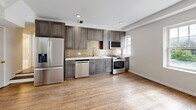 Located at 5-9 Del Lin Dr, Unit 201 in Saint Louis, MO, this thoughtfully designed unit offers four bedrooms and three bathrooms across a single floor. Rich hardwood flooring flows throughout, lending warmth and continuity to every room.

The kitchen is a standout feature, outfitted with sleek gray shaker cabinetry extending floor to ceiling, a warm brick-style tile backsplash, white quartz countertops, a gold-finish faucet, and a full suite of stainless steel appliances including a gas range, built-in microwave, dishwasher, and refrigerator.

The bedrooms are bright and clean, with neutral walls, hardwood floors, and built-in closet shelving for organized storage. Several rooms include ceiling fans and windows that bring in natural light and views of the surrounding neighborhood.

The bathrooms are elegantly finished with sculptural textured wall tile in warm taupe tones, brushed gold fixtures and hardware, soaking tubs with glass enclosures, and white vanities topped with clean countertops. The overall aesthetic is cohesive and refined throughout.

A connecting hallway ties all rooms together in a functional layout. The unit combines modern convenience with upscale design details, making it a well-appointed residence in the Saint Louis area.