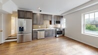 Located at 5-9 Del Lin Dr, Unit 201 in Saint Louis, MO, this thoughtfully designed unit offers four bedrooms and three bathrooms across a single floor. Rich hardwood flooring flows throughout, lending warmth and continuity to every room.

The kitchen is a standout feature, outfitted with sleek gray shaker cabinetry extending floor to ceiling, a warm brick-style tile backsplash, white quartz countertops, a gold-finish faucet, and a full suite of stainless steel appliances including a gas range, built-in microwave, dishwasher, and refrigerator.

The bedrooms are bright and clean, with neutral walls, hardwood floors, and built-in closet shelving for organized storage. Several rooms include ceiling fans and windows that bring in natural light and views of the surrounding neighborhood.

The bathrooms are elegantly finished with sculptural textured wall tile in warm taupe tones, brushed gold fixtures and hardware, soaking tubs with glass enclosures, and white vanities topped with clean countertops. The overall aesthetic is cohesive and refined throughout.

A connecting hallway ties all rooms together in a functional layout. The unit combines modern convenience with upscale design details, making it a well-appointed residence in the Saint Louis area.