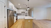 Located at 3361 W Jordan Line Pkwy in West Jordan, Utah, this contemporary single-floor residence offers a clean, modern aesthetic with a cohesive design language carried throughout every room. The open-concept kitchen serves as the heart of the home, showcasing crisp white cabinetry with brushed nickel hardware, a classic subway tile backsplash, and a full suite of stainless steel appliances including a refrigerator, range, microwave, and dishwasher. A central island with a light wood base and white quartz-style countertop provides additional prep space and is illuminated by stylish black pendant lights. Light wood-tone flooring flows seamlessly through the kitchen and into the living areas, creating a warm, unified feel. The bedrooms are bright and well-proportioned, with large windows fitted with horizontal blinds that invite natural light. One bedroom includes access to a spacious walk-in closet outfitted with wire shelving. A patio door with sidelights opens to an outdoor space, further enhancing the sense of openness. The primary bathroom features a double-sink vanity with white cabinetry, a large mirror, and a soaking tub with shower combination. A secondary bathroom offers a single vanity and a separate shower. Clean white walls and consistent flooring throughout give the entire space a bright, move-in-ready appeal.