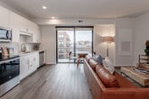 Located at 331 Westport Rd in Kansas City's vibrant Westport neighborhood, this single-floor residence offers a thoughtfully designed open-concept layout with modern finishes throughout. The living area is bright and welcoming, featuring warm hardwood-style flooring, recessed lighting, and a large sliding glass door that opens to a private balcony with views of the surrounding neighborhood skyline — allowing abundant natural light to fill the space.

The kitchen is well-appointed with white shaker cabinetry, white quartz countertops, a classic subway tile backsplash, and a full suite of stainless steel appliances including a refrigerator, range, over-the-range microwave, and dishwasher. It flows seamlessly into the dining and living areas, making it ideal for everyday living and entertaining.

The living room comfortably accommodates a generous seating arrangement and media setup, with warm ambient lighting adding to the inviting atmosphere. The bedroom offers a quiet, neutral retreat with soft carpeting and ample wall space. The bathroom is clean and modern, featuring a tiled tub-shower combination, a white vanity with storage, and hardwood-style flooring that carries through from the rest of the unit.