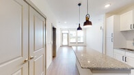 This single-floor unit is designed with a clean, contemporary aesthetic throughout. The kitchen serves as a central highlight, featuring white shaker cabinetry with matte black hardware, granite countertops, and a full suite of stainless steel appliances including a French door refrigerator, range, microwave, and dishwasher. A large granite-topped island anchors the space and is illuminated by two industrial-style pendant lights, creating a functional and stylish focal point. Light wood-look flooring runs through the kitchen and living areas, contributing to a bright, open feel. The living area benefits from multiple windows and a ceiling fan, allowing natural light to fill the space, with a door providing direct outdoor access.

The bedrooms are finished with plush carpeting and ceiling fans, with windows offering exterior views. One bedroom includes a generously sized walk-in closet outfitted with multiple shelving rods and carpeted flooring for comfort. The unit includes two full bathrooms, each featuring granite vanity countertops, white cabinetry, and tub-shower combinations with white tile surrounds. Recessed lighting and a neutral color palette throughout lend the unit a polished, move-in-ready appearance.