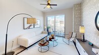 Located at 9600 S Dixie Hwy in Miami, Florida, this stylish high-rise residence offers a thoughtfully designed single-floor layout with modern finishes and striking artistic details throughout. The living area is bright and open, featuring light wood flooring, a ceiling fan, and floor-to-ceiling sliding glass doors that lead to a private balcony. The outdoor space provides expansive views of the Miami skyline, making it a standout feature of the home.

The kitchen is outfitted with wood-tone cabinetry extending to the ceiling, stainless steel appliances including a side-by-side refrigerator, electric range, microwave, and dishwasher, along with white countertops and a dining area with a glass table and cane-back chairs.

The bedroom is a design focal point, featuring bold black-and-white abstract wallpaper that wraps the walls, a wood-framed platform bed, and large windows that frame sweeping views of the surrounding cityscape and lush greenery below. A floating dark console with curated décor and sculptural wall art adds an artistic touch.

The bathroom is finished with light wood cabinetry, a white countertop with an undermount sink, a large wall mirror, and neutral tile flooring. The overall aesthetic of the residence is clean and contemporary, balancing artistic expression with functional, modern living in the heart of Miami.