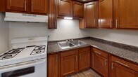 Located at 214 E Napoleon Rd in Bowling Green, Ohio, this single-floor unit offers a practical and comfortable layout designed for everyday living. The living area greets occupants at the entrance, featuring durable wood-look flooring, neutral walls, and multiple windows that allow natural light to fill the space. A wall-mounted HVAC unit provides climate control, and a front door with glass panel inserts adds a welcoming touch.

The kitchen is a standout feature, showcasing rich, warm-toned cabinetry with modern hardware, dark granite-style countertops, a double stainless steel sink, and a white gas range with under-cabinet lighting. Wood-look flooring continues throughout this area, complementing the cabinetry and creating a cohesive aesthetic.

The bedrooms are carpeted and finished with neutral tones, each offering windows with blinds that provide natural light and privacy. The rooms are generously sized and versatile in their use.

The bathroom is clean and functional, featuring wood-look flooring, a white vanity with an integrated sink, a mirrored medicine cabinet above, and a separate water closet with a bathtub and towel rod. The layout provides efficient use of the available space.

Overall, this unit presents a well-maintained, move-in-ready space with consistent finishes throughout.
