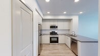 Located at 531 W Crowther Ave in Placentia, CA, this thoughtfully designed two-bedroom, two-bathroom apartment offers a clean, modern aesthetic throughout its efficiently arranged single floor. The open-concept kitchen serves as a centerpiece, featuring flat-front white cabinetry extending to the ceiling, a full suite of stainless steel appliances including a gas range, over-the-range microwave, refrigerator, and dishwasher, paired with sleek grey quartz countertops and a peninsula that overlooks the main living area. Light wood-style flooring flows through the kitchen and hallways, lending warmth to the bright, neutral palette. The two bedrooms are carpeted for comfort, with the primary bedroom offering dedicated closet access and an en-suite bathroom. The second bedroom benefits from a large window that brings in natural light and outdoor views. Both bathrooms are finished with grey quartz countertops, white cabinetry, undermount sinks, and wood-look tile flooring; one includes a tub-shower combo with white tile surround, while the other features a dual-sink vanity. Three hallways connect the rooms, and two closets provide practical storage. Recessed lighting throughout maintains a bright, contemporary ambiance.
