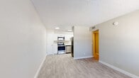 Located at 550 N Pantano Rd in Tucson, Arizona, this one-bedroom, one-bathroom unit offers a practical and well-appointed layout across a single floor. The open-concept kitchen and living area serves as the heart of the space, featuring light gray vinyl plank flooring and a textured ceiling. The kitchen is outfitted with white shaker cabinetry, clean white countertops, and a full suite of stainless steel appliances including a range, microwave, dishwasher, and refrigerator, all illuminated by a flush overhead light panel. The living area provides a bright, neutral backdrop with a window that invites natural light and views of the surrounding neighborhood. A hallway connects the main living area to the private bedroom and bathroom. The bedroom is finished with plush carpeting, a window with blinds for natural light and privacy, and a dedicated walk-in closet offering ample storage. The bathroom features a white vanity, tiled tub-shower combo, and wood-look vinyl flooring, maintaining a clean and cohesive aesthetic throughout. Neutral warm-gray wall tones and crisp white trim unify the space, creating a simple, move-in-ready environment suited for comfortable single-occupancy living in Tucson.