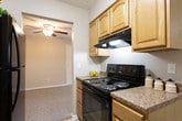 Located at 1040 Shive Ln in Bowling Green, Kentucky, this single-floor unit offers a practical and well-organized layout suited for comfortable everyday living. The spacious living room features neutral-toned carpet, a ceiling fan with light fixture, and a sliding glass door flanked by vertical blinds that invite natural light and provide outdoor access. A secondary living or dining area connects seamlessly to the kitchen, which is outfitted with warm wood cabinetry, granite-style countertops, tile flooring, and black appliances including a refrigerator and electric range. Two carpeted bedrooms are finished in soft neutral tones, each featuring windows with blinds that allow for natural light and outdoor views. The primary bathroom includes an extended vanity with wood cabinetry and a light countertop, offering generous storage, with a separate water closet featuring a shower and tub combination. A second full bathroom provides a wood-cabinet vanity with a white countertop and a mirrored medicine cabinet above. Throughout the unit, clean white trim, consistent neutral wall colors, and functional design elements create a cohesive and move-in-ready living environment.