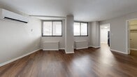 Located at 1131 University Blvd W in Silver Spring, MD, this thoughtfully designed single-floor unit makes excellent use of its compact footprint. Rich, dark hardwood-style flooring runs throughout the space, adding warmth and visual continuity from room to room.

The open living area is bright and welcoming, featuring two large windows dressed with horizontal blinds that allow for ample natural light and views of the surrounding neighborhood. A wall-mounted mini-split unit provides efficient climate control, while built-in radiator covers beneath the windows contribute to the space's clean, finished look.

The kitchen is well-equipped with white shaker-style cabinetry, light quartz countertops, and a suite of black Frigidaire appliances including a gas range, over-the-range microwave, and dishwasher. A deep single-basin sink with a matte black faucet completes the functional and stylish kitchen setup.

Storage is well-addressed throughout the unit, with two closets featuring louvered bifold doors — one conveniently located in the main living area and another accessible from the bedroom space. A hallway connects the key areas of the unit, leading to a full bathroom. The neutral gray walls and white trim maintain a clean, modern aesthetic throughout the entire space.