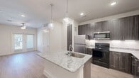 Located at 4909 E Lancaster Ave in Fort Worth, TX, this thoughtfully designed 2-bedroom, 2-bathroom residence offers a clean, modern aesthetic throughout. Light wood-look flooring flows seamlessly across all rooms, complemented by crisp white walls and clean baseboards that create a bright, airy atmosphere.

The kitchen is a standout feature, boasting rich dark wood cabinetry, granite countertops with subtle veining, a central island with a single-basin sink and pendant lighting overhead, and a full suite of stainless steel appliances. Ample upper and lower cabinetry, including a tall pantry cabinet, ensures generous storage.

Both bedrooms are well-proportioned and bright. The primary bedroom benefits from natural light through a window with blinds and is equipped with a ceiling fan. Each bedroom is served by its own closet, with the primary featuring a walk-in closet outfitted with built-in shelving and hanging rods for excellent organization.

The two bathrooms are finished with granite vanities and wood-look flooring. One bathroom includes a tub-shower combination with clean white tile surround. A dedicated laundry area with washer and dryer hookups adds everyday convenience. A connecting hallway ties the layout together, making this residence as functional as it is stylish.
