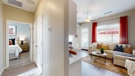 This single-story residence offers a thoughtfully designed open-concept layout that seamlessly connects the kitchen, dining, and living areas. The kitchen is a standout feature, outfitted with crisp white shaker cabinetry, light quartz countertops, stainless steel appliances including a range, over-the-range microwave, and refrigerator, and a central island with bar seating — ideal for casual dining and entertaining. Wood-look flooring runs throughout, adding warmth and cohesion to the space.

The living room is inviting and well-lit, benefiting from multiple windows that allow natural light to flow in. A ceiling fan adds comfort, while a sliding glass door provides access to the outdoors. The room accommodates a generous sectional sofa and features neutral grey walls accented by bold drapery.

The bedroom is a calm retreat, featuring a ceiling fan, a sliding-door closet with built-in shelving, and warm, neutral tones that create a restful atmosphere. Ample natural light enhances the sense of space.

The bathroom is clean and efficiently laid out, with white cabinetry, a light countertop, a window for natural ventilation, and the same wood-look flooring found throughout the home. A hallway with multiple closet doors provides additional storage, completing this practical and comfortable residence.
