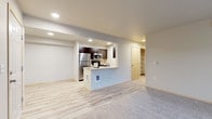 This single-floor residence offers a thoughtfully designed layout that balances comfort and functionality. The open-concept living and kitchen area serves as the heart of the unit, where light wood-look flooring transitions seamlessly from the kitchen into the living space. The kitchen is outfitted with dark espresso cabinetry, stainless steel appliances including a refrigerator, microwave, and range, and a peninsula counter that provides additional workspace and a natural divider between the two areas. Recessed lighting illuminates the kitchen, adding a clean, modern touch. The living room is generously sized with plush carpeting and features a sliding glass door that opens to a private balcony, allowing for natural light and outdoor views of the surrounding neighborhood. The bedrooms are carpeted and well-proportioned, with windows fitted with blinds for privacy and light control. A spacious walk-in closet with wire shelving offers ample storage. The bathroom includes a single-sink vanity with modern hardware and a full tub-shower combination. A dedicated in-unit laundry area with a washer provides added everyday convenience. Neutral tones throughout create a bright, clean, and move-in-ready atmosphere.
