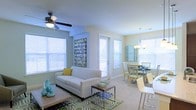 Located at 320 The Green Cir in Raleigh, NC, this single-floor residence offers a welcoming and well-lit interior defined by an open-concept layout that seamlessly connects the living and dining areas. Large windows dressed with white horizontal blinds flood the space with abundant natural light, creating an airy and inviting atmosphere throughout.

The living area is comfortably proportioned, featuring light-toned carpet flooring and a ceiling fan that adds both functionality and a casual aesthetic. A patterned area rug anchors the seating arrangement, which centers around a classic sofa accented with decorative pillows. The neutral wall tones enhance the brightness of the room and provide a versatile backdrop for varied décor styles.

Adjacent to the living space, the dining area transitions smoothly, highlighted by an elegant pendant chandelier that adds a touch of sophistication. The dining setup accommodates a generous number of seats, making it suitable for both everyday meals and entertaining. A door with glass panels allows additional natural light to enter while providing access to the outdoors. Together, the rooms convey a cohesive, comfortable, and functional living environment.