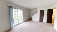 Rose is a two-story, 3-bedroom, 1.5-bathroom home designed with a clean, functional layout across two levels. The main floor features a generously sized living area with soft wall-to-wall carpeting and a sliding glass door that fills the space with natural light and provides views of the surrounding greenery. Adjacent to the living area, the galley-style kitchen is equipped with dark wood cabinetry, a stainless steel sink, a dishwasher, a refrigerator, and an electric range, all complemented by tile flooring and a window that lets in additional natural light. The main floor also includes a convenient half bathroom and storage closets accessible from the living space, along with a staircase leading to the upper level. Upstairs, three carpeted bedrooms offer comfortable, well-proportioned spaces, each with windows that bring in natural light and outdoor views. The full bathroom on the upper level features tile flooring, a tub-shower combination, a large vanity with an extended countertop, and a bright window. Throughout the home, the neutral color palette and clean finishes provide a versatile backdrop well-suited for a variety of living styles.