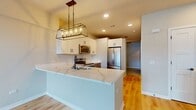 This contemporary 680 square foot apartment in Elgin, IL, showcases a well-designed two-story layout. The ground floor, comprising 70 square feet, likely houses the entrance and staircase. The main living space, spanning 610 square feet, is on the upper floor.

The heart of the home is an open-concept kitchen and living area. The kitchen boasts white cabinetry, stainless steel appliances, and a striking marble-look countertop. A modern rectangular chandelier hangs over the kitchen island, adding a touch of elegance.

Large windows with plantation shutters flood the living area with natural light, offering views of the surrounding neighborhood. The space features light-toned hardwood flooring throughout, creating a sense of warmth and continuity.

The bathroom, while compact, is efficiently designed with a vanity, toilet, and necessary fixtures. It maintains the apartment's modern aesthetic with clean lines and a neutral color palette.

Architectural details include shiplap accent walls, adding texture and visual interest. The apartment's doors are painted white, matching the overall color scheme and contributing to the bright, airy feel of the space.

This apartment combines functionality with style, making excellent use of its modest square footage to create a comfortable and attractive living environment.