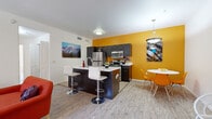 This well-appointed 3-bedroom, 2-bathroom apartment in Tucson, Arizona offers a thoughtfully designed single-floor layout that maximizes functionality and style. The open-concept living, dining, and kitchen area serves as the heart of the home, featuring light wood-style flooring, a bold golden-yellow accent wall, and seamless flow between spaces. The kitchen is equipped with stainless steel appliances, including a refrigerator, range, and microwave, complemented by dark cabinetry, a central island with a white countertop and bar seating, and a double-basin sink. The adjacent dining area features a round white table with vibrant orange chairs, adding a lively, modern touch. The living room offers a ceiling fan, sliding glass door that brings in natural light, and direct outdoor access. Each of the three bedrooms features light wood-style flooring and sliding closet doors with built-in shelving. The two bathrooms are clean and functional, with one featuring a tub-shower combination and dark wood vanity with a white countertop. A dedicated in-unit laundry room with a full-size washer and dryer adds everyday convenience. The overall ambiance is bright, colorful, and modern, making this a practical and inviting Tucson residence.