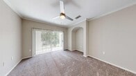 This single-story, 2-bedroom, 1-bathroom residence offers a thoughtfully designed layout across a comfortable footprint. The living room serves as the central gathering space, featuring plush carpeting, crown molding, a ceiling fan with light fixture, and a wide sliding glass door framed by vertical blinds that floods the room with natural light and provides outdoor views. A distinctive arched alcove adds an architectural accent to the space.

The galley-style kitchen is well-equipped with stainless steel appliances, including a refrigerator, range, and built-in microwave. Gray lower cabinetry is paired with white upper cabinets and light quartz countertops, complemented by a stainless steel sink and light wood-tone vinyl plank flooring.

The primary bedroom offers a generous layout with carpeting, a ceiling fan, crown molding, and a sliding glass door that opens to the outdoors. It is served by a spacious walk-in closet with multi-tier wire shelving on three walls. The second bedroom features carpet, a ceiling fan, and a window with natural light.

The bathroom includes a quartz-topped vanity with gray cabinetry and a wide mirror. A dedicated in-unit laundry room houses a full-size washer and dryer with wire shelving above.