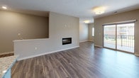 This single-floor residence offers a thoughtfully designed open-concept layout that seamlessly connects the main living and kitchen areas. The living room is finished with rich hardwood-style flooring and features a built-in fireplace set into a dedicated accent wall, creating a functional focal point. A sliding glass door leads to a private balcony, allowing natural light to fill the space while providing outdoor views. A secondary window further brightens the room.

The kitchen is outfitted with white shaker-style cabinetry, granite countertops, and a full suite of stainless steel appliances, including a refrigerator with ice maker, range, and built-in microwave. A granite-topped peninsula with an undermount sink offers additional workspace and casual seating potential. Pendant lighting above the peninsula adds a polished finish.

The bedrooms are carpeted for comfort, each featuring ceiling fans and ample natural light. The primary bedroom includes a walk-in closet. The bathroom is equipped with a soaking tub and shower combination, a white vanity with granite countertop, and tile flooring. A dedicated in-unit laundry area with washer and dryer connections adds everyday convenience throughout this well-finished residence.