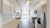This well-appointed single-floor residence offers a thoughtfully designed layout with high-end finishes throughout. The expansive living area is bathed in natural light from oversized windows framing sweeping city and treetop views, and is anchored by an elegant chandelier and rich, dark hardwood-style flooring. Crown molding adds a refined architectural detail, while neutral walls create a clean, versatile backdrop. A tray ceiling detail further enhances the sense of space and sophistication.

The galley-style kitchen is both functional and stylish, featuring crisp white shaker cabinetry with matte black hardware, gleaming granite countertops, a classic subway tile backsplash, and stainless steel appliances including a gas range, built-in microwave, and dishwasher. A bay window at the end of the kitchen allows natural light to fill the space.

The primary bathroom is a standout retreat, offering a large jetted soaking tub, a glass-enclosed walk-in shower with rainfall fixtures, a dual-sink vanity with granite countertops, and warm tile flooring. Additional conveniences include a dedicated laundry room with full-size washer and dryer units and built-in shelving, as well as a closet with rod and shelf storage. The overall ambiance is modern, clean, and move-in ready.