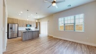 Located in Broken Arrow, Oklahoma, this well-appointed single-story home showcases a contemporary design with a cohesive, light-toned aesthetic throughout. Wood-look luxury vinyl flooring flows seamlessly across every room, complementing the neutral wall palette and clean white trim.

The open-concept living and kitchen area serves as the heart of the home. The living space is bathed in natural light through large windows with blinds and a sliding glass door that opens to an outdoor area. A ceiling fan keeps the space comfortable year-round. The kitchen is equipped with stainless steel appliances, including a refrigerator, microwave, and range, and features a substantial island with a granite countertop, an undermount sink, and a built-in dishwasher. Light wood cabinetry extends to the upper walls, providing generous storage.

The bedrooms are well-proportioned, each featuring windows that bring in natural light and ample wall space. The primary suite includes an en-suite bathroom with a granite-topped vanity, a walk-in glass-enclosed shower, and direct access to a walk-in closet. A secondary bathroom offers a full tub-shower combination and a matching granite vanity. The thoughtful layout and modern finishes make this home a functional and attractive residence.