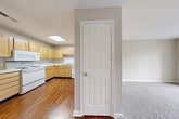 This two-bedroom, two-bathroom single-floor residence in Greensboro, NC offers a well-organized layout designed for comfortable everyday living. The kitchen is a functional highlight, featuring light wood cabinetry, granite-style countertops, a full suite of white appliances including a range, dishwasher, microwave, and refrigerator, and rich hardwood-style flooring. A skylight overhead floods the space with natural light, creating a bright and welcoming atmosphere. The kitchen opens toward the living areas, which are carpeted in neutral tones and include large windows that bring in additional natural light and views of the surrounding community. The spacious primary bedroom is generously sized, fitted with plush carpet, a ceiling fan, a closet with bifold doors, and windows on two walls offering ample natural illumination. The second bedroom is equally well-lit, with soft carpet and a large window. Both bathrooms are clean and functional, each featuring a tub/shower combo with chrome fixtures and wood-style flooring. Three closets throughout the unit provide practical storage solutions. A connecting hallway ties the layout together efficiently. Neutral wall tones and consistent finishes throughout give the space a cohesive, move-in-ready appearance.