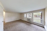 This efficiently designed one-bedroom, one-bathroom residence offers a well-organized layout across a single floor, making practical use of every square foot. The living room serves as the heart of the unit, featuring neutral-toned carpet, soft beige walls, and generous natural light streaming in through large windows and a glass-paneled exterior door that opens to a balcony with views of the surrounding greenery and neighboring buildings. Baseboard heating runs along the walls, ensuring consistent warmth throughout the space. The kitchen is laid out in a galley style, with warm wood cabinetry extending to the ceiling, light countertops, a built-in sink, a gas range, and a full-size refrigerator — all set atop easy-care tile flooring. The bedroom is a comfortably sized retreat with soft carpet underfoot, neutral walls, a window that brings in natural light, and access to multiple closets, offering ample storage. The bathroom features tile flooring and a full shower-tub combination with a clean, simple surround. A connecting hallway ties the rooms together seamlessly. With three closets distributed throughout the unit, storage is a notable practical advantage of this thoughtfully arranged residence.