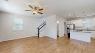 Located at 2314 Doveshell Dr in North Myrtle Beach, SC, this two-story home offers a well-designed layout with thoughtful finishes throughout. The main level features an open-concept living and kitchen area with durable wood-look flooring, recessed lighting, and a ceiling fan. The kitchen is a standout, showcasing white shaker cabinetry, granite countertops, a central island with pendant lighting, and a full suite of stainless steel appliances including a refrigerator with ice maker, range, microwave, and dishwasher. A convenient half bath with wood-look tile flooring is also located on the main level. A staircase with a classic black railing connects the floors. The upper level hosts generously sized bedrooms finished with plush carpeting and ceiling fans. The primary bedroom features a tray ceiling, adding an elegant architectural detail, along with multiple windows that invite natural light. Additional bedrooms share access to a full bathroom with a tub-shower combination. A utility area on the upper level houses the water heater. Throughout, the home maintains a clean, neutral palette with white walls and trim, creating a bright and versatile living environment.