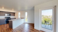 This thoughtfully designed one-bedroom unit offers a functional and modern living experience across a single floor. The open-concept layout seamlessly connects the kitchen and living area, creating a bright, airy atmosphere enhanced by multiple tall, narrow windows that invite abundant natural light and frame views of surrounding greenery.

The kitchen is a standout feature, equipped with dark wood cabinetry, black appliances including a range, over-the-range microwave, dishwasher, and refrigerator, along with neutral-toned countertops. A peninsula with a built-in sink adds additional prep space and serves as a natural divider between the kitchen and living area. Recessed lighting and a ceiling fan keep the space comfortable and well-lit.

Rich hardwood-style flooring runs throughout the entire unit, lending warmth and continuity to each room. The living area is generously sized, offering a versatile open space with access to a private balcony through a glass door — ideal for enjoying outdoor views.

The bedroom is a comfortable, well-proportioned room featuring a ceiling fan, a window with natural light, and direct access to a closet. Clean white walls throughout the unit provide a neutral canvas, while the modern finishes give the space a contemporary, move-in-ready appeal.