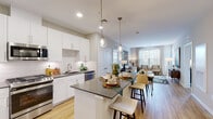This single-floor residence offers a thoughtfully designed open-concept layout that seamlessly connects the kitchen, dining, and living areas. The kitchen is outfitted with white shaker-style cabinetry, dark quartz countertops, a subway tile backsplash, and a full suite of stainless steel appliances, including a gas range, built-in microwave, dishwasher, and refrigerator. A central island with bar seating and pendant lighting serves as a natural gathering point, flowing into the dining and living spaces. The living room is bright and airy, benefiting from large windows dressed with sheer curtains that invite generous natural light and outdoor views.

The unit features two well-proportioned bedrooms, each with plush carpeting, large windows, and ample natural light. The primary bathroom includes a glass-enclosed walk-in shower with tile surround and light tile flooring, while the secondary bathroom offers a full soaking tub with a shower curtain, a dark-vanity with integrated sink, and matching tile flooring. Light wood-style flooring runs throughout the main living areas, unifying the space with a warm, contemporary aesthetic. Recessed lighting and pendant fixtures provide layered illumination throughout.
