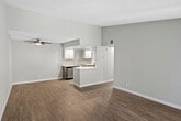 Located at 3900 Fir Tree Dr in Riverside, California, this single-floor unit offers a clean, modern aesthetic throughout. The open-concept living area is finished with warm-toned vinyl plank flooring and neutral gray walls, creating a bright and cohesive atmosphere. A ceiling fan adds both style and function to the main living space, which flows seamlessly into the kitchen via a half-wall pass-through. The kitchen is well-appointed with white upper cabinetry, contemporary dark lower cabinets, light quartz-style countertops, recessed lighting, and a full suite of stainless steel appliances including a range, over-the-range microwave, and dishwasher. The layout maximizes functionality with generous counter space on both sides. The bedroom is comfortably sized, featuring its own ceiling fan with light, corner windows that invite natural light, and wood-look plank flooring. Closet access is conveniently located near the room's entry. The bathroom is neatly finished with wood-look flooring, a combined tub and shower, toilet, and a vanity with storage. Textured walls throughout add a subtle design element, while the overall interior palette of soft grays and whites lends a fresh, move-in-ready feel to this well-updated Riverside residence.