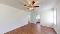 Located at 3003 E Southcross Blvd in San Antonio, Texas, this single-floor unit offers a straightforward and functional layout with consistent wood-look flooring running throughout every room, creating a cohesive and easy-to-maintain living environment. The living area is spacious and bright, featuring crisp white walls, a ceiling fan with integrated lighting, and natural light filtering in through multiple windows fitted with blinds. An open pass-through connects the living space to the kitchen, which is outfitted with white cabinetry, a refrigerator, and a range, along with a window that brings in additional natural light. A back door in the kitchen area provides convenient secondary access to the exterior. The bedroom offers a comfortable, private retreat with its own closet featuring a built-in rod for hanging storage, and a window that lets in natural light. The bathroom is clean and functional, with a vanity and sink, a tub-shower combination, a toilet, and a window for ventilation. Throughout the unit, white walls and trim contribute to a bright, neutral palette, making the space easily adaptable to a variety of furnishing styles. The layout is compact and efficient, designed to maximize usability across all areas of the home.